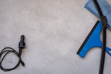 Silecek bıçağı, cam kazıyıcı, mikrofiber bez ve bir de çakmağın şarj aleti. Cam Kazıma Aracı veya Gri arka planda Duş, Pencere ve Araba Camları için Squeegee