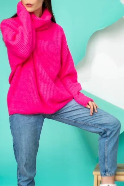 배경을 배경으로 분홍색 포즈를 취하고 소녀가 광고를 찍거나 용하고 스웨터를 — 스톡 사진