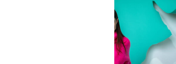Banner girl without a face in jeans and a pink sweater on a blue background. Mock up for your text or advertisings. Cute girl in playful mood posing. Young brunette in knitted sweater plays hair.