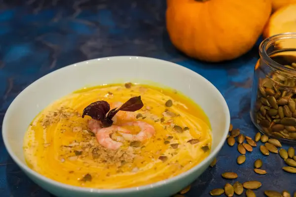 Tasty pumpkin cream soup with shrimps and basil leaves, blended with spice and carrots. Top view. — Stock Image Tasty Pumpkin Cream Soup Shrimps Basil Leaves Blended Spice Carrots Stock Photo