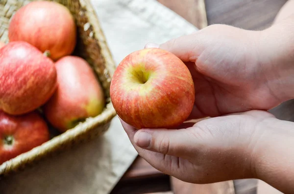 Cesta de maçãs e uma maçã na mão de uma criança — Fotografia de Stock