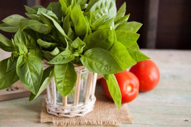 Demet taze yeşil fesleğen ve ahşap masa üzerinde domates