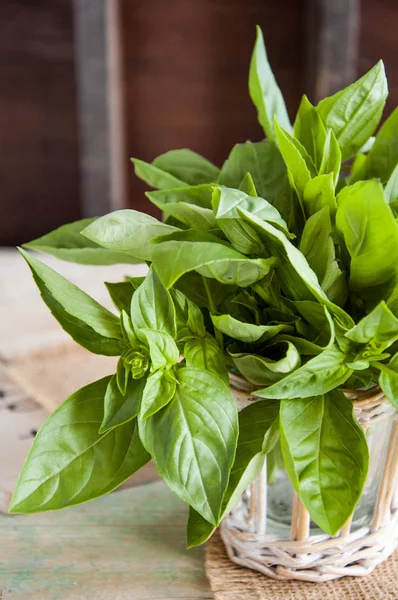 Tahta arka planda taze yeşil fesleğen yaprakları.