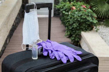 Seyahat çantası, antibakteriyel sabun, tek kullanımlık eldiven ve tıbbi maske. Coronavirüs salgını sırasında seyahat yasağı ve karantina konsepti.