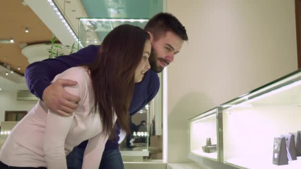 Пара смотрит на торговый дисплей с ювелирными изделиями в магазине — стоковое видео