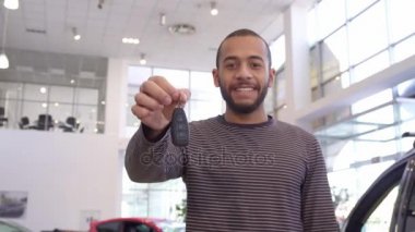 Adam arabanın anahtarını galeride gösterir.