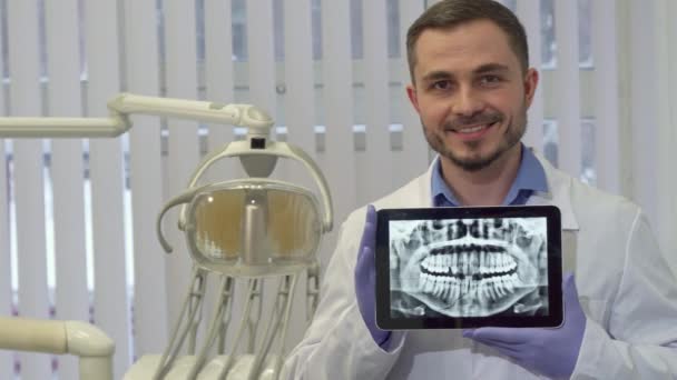 Dentista demuestra la radiografía de dientes humanos en su tableta — Vídeo de stock