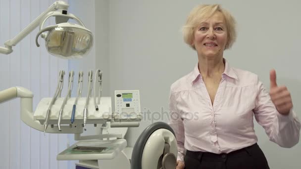 Äldre kvinna visar sin tumme vid det tandläkare kontoret — Stockvideo