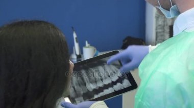 Diş hekimi hastanın x-ray tablet üzerinde gösterir.