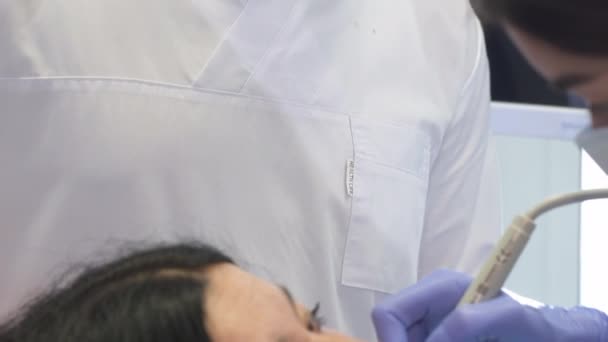 Стоматолог проводит ультразвуковую очистку для женщины — стоковое видео