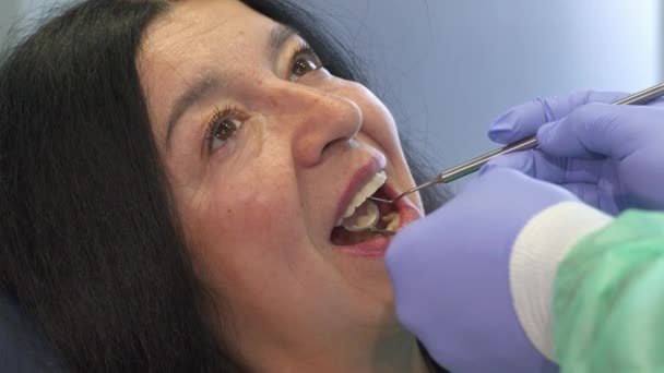 歯科医は、クライアント口の中で歯科用器具を保持しています。 — ストック動画