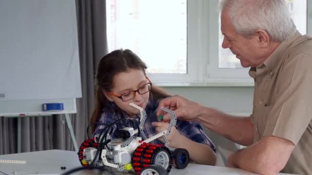 Senior man gives his granddaughter the part from toy vehicle — Stock Video