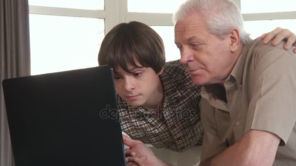 Niño ayudando a su abuelo con el ordenador portátil — Vídeos de Stock