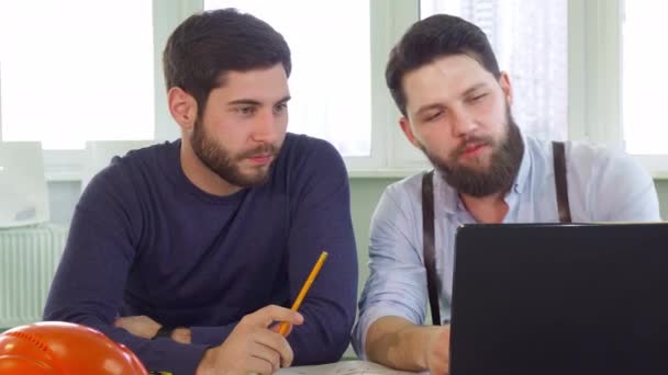 Два архитектора смотрят на экран ноутбука — стоковое видео