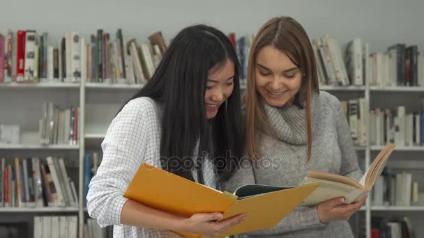Two female students compare information in two books at the library