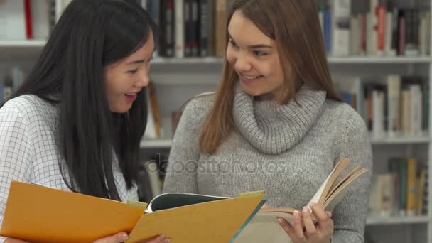 Studentka ukazuje její ukazováček do knihy v knihovně — Stock video