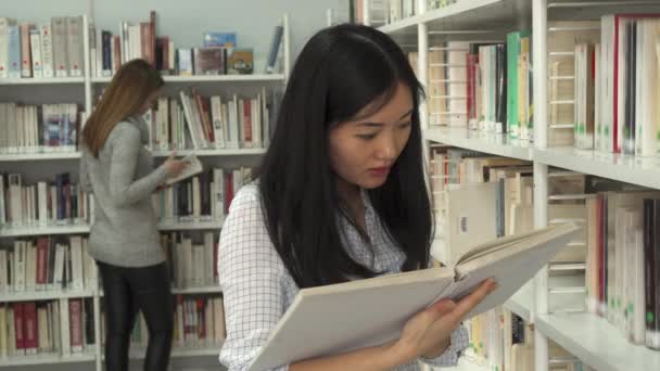 Studentin liest Buch in der Bibliothek — Stockvideo