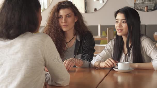 Duas meninas ouvindo atentamente seu amigo no café — Vídeo de Stock