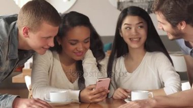Dört arkadaş kafede smartphone cep telefonu ile bir şey izlemek