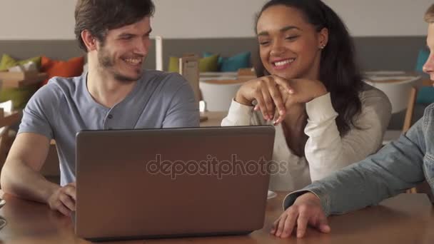 Jóvenes sonriendo sobre lo que ven en el portátil en el café — Vídeos de Stock