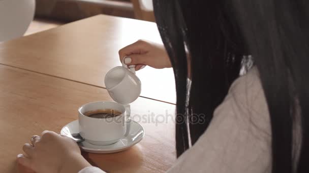 Meisje voegt room in haar koffie in het café — Stockvideo