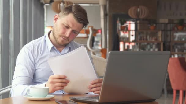 Бизнесмен просматривает какие-то бумаги в кафе — стоковое видео
