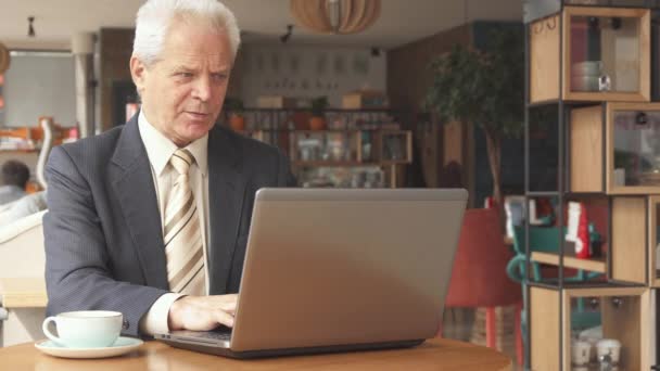 Senior zakenman gebruikt laptop in het café — Stockvideo