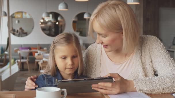 Madre e hija usan tabletas en la cafetería — Vídeo de stock