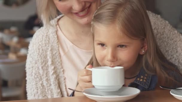 Маленькая девочка делает глоток чая в кафе — стоковое видео