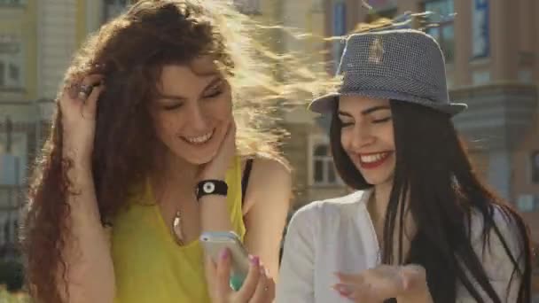 Две девушки обсуждают что-то на смартфоне — стоковое видео