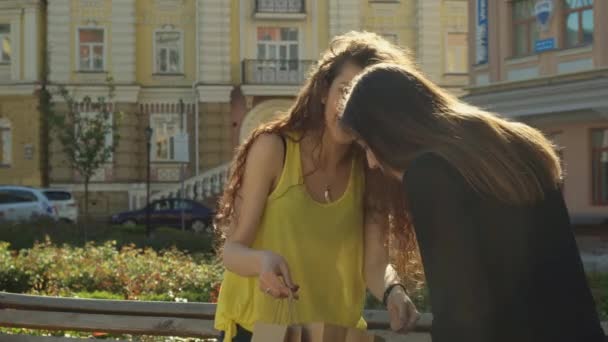 Amigos femininos olham dentro do saco de compras — Vídeo de Stock