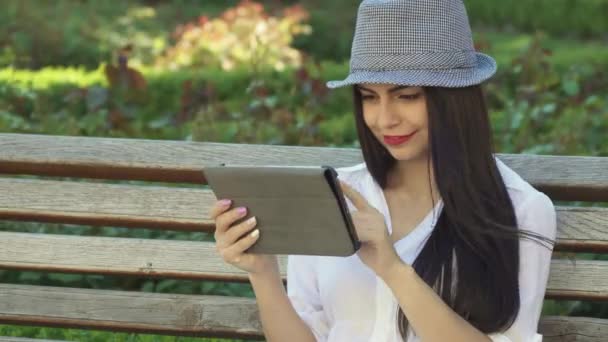 Girl uses tablet on the bench — Stock Video