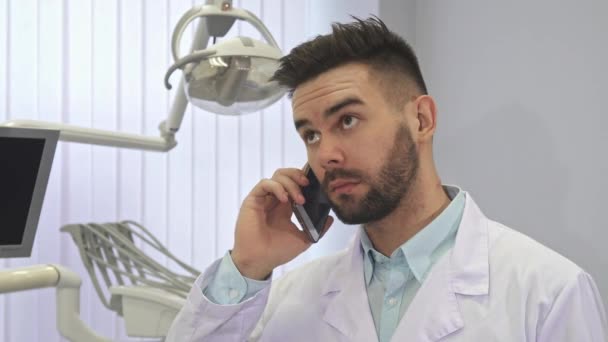 Стоматолог розмовляє по телефону в офісі — стокове відео