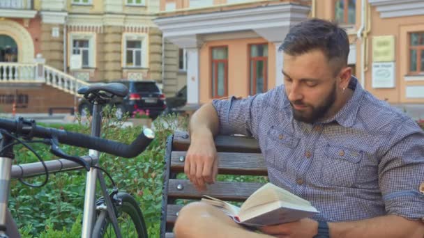Ciclista gira la pagina del libro sulla panchina — Video Stock