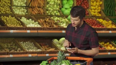 Adam akıllı telefon süpermarkette kullanır.