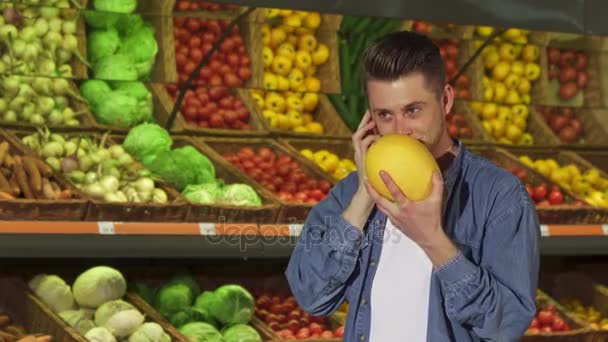 Чоловік пахне динею в супермаркеті — стокове відео