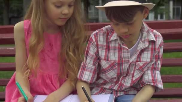 Children draw in the album together on the bench — Stock Video