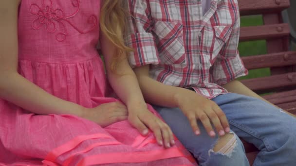 Petit garçon met les filles main sur le genou sur le banc — Video