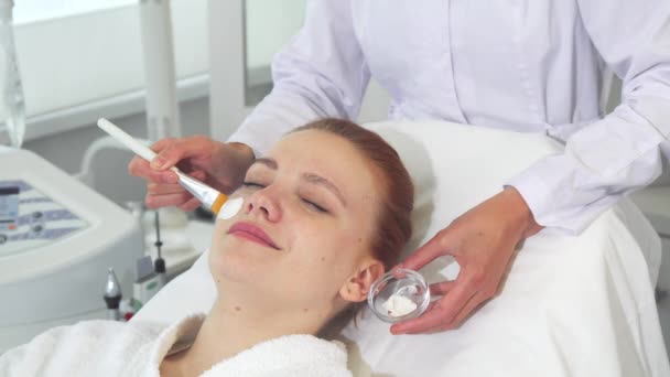 Косметолог наносит крем на лицо клиента — стоковое видео
