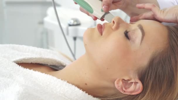 Cosmetólogo usando fregador ultrasónico en la cara de los clientes — Vídeo de stock