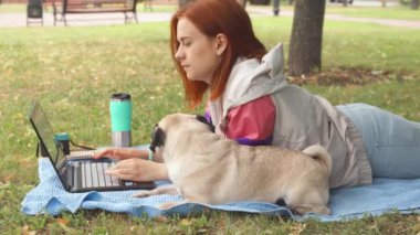 Döşeme ve laptop ile onun pug bir çimenlikte tipik kız