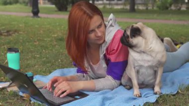 Döşeme ve laptop ile onun pug bir çimenlikte tipik kız