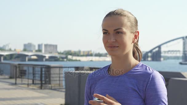 Woman drinks water and shows thumb up against urban background — Stock Video