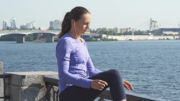 女性が運動する前に彼女の足を伸ばす — ストック動画