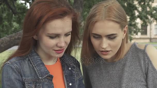 Chicas sonriendo ang hablando mientras comparten el teléfono — Vídeos de Stock