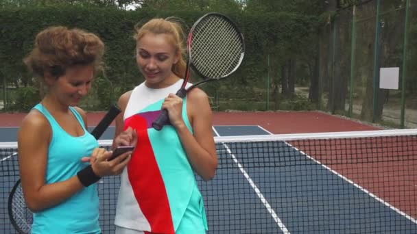 Two tennis girls discussing while sharing a smartphone — Stock Video