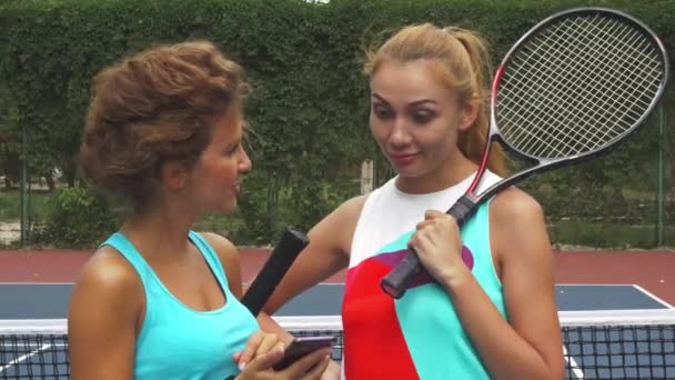 Закрытие двух теннисных девочек, обсуждающих во время совместного пользования смартфоном — стоковое видео