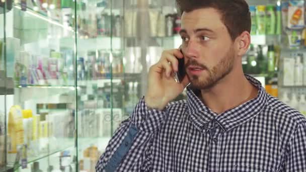 Uomo che parla al telefono di pillole in farmacia — Video Stock