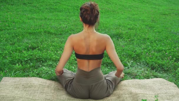 Girl is siiting in the yoga mat and doing one of the yoga poses — Stock Video