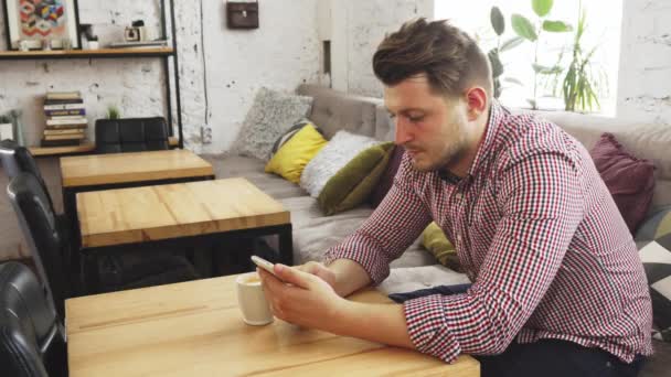 O cliente está usando seu telefone enquanto bebe café — Vídeo de Stock
